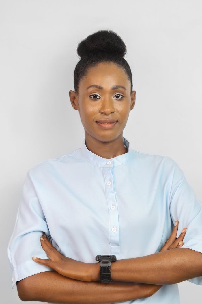 our-stories Portrait of a confident African businesswoman in Lagos, Nigeria, wearing a blue shirt and smiling with arms crossed.
