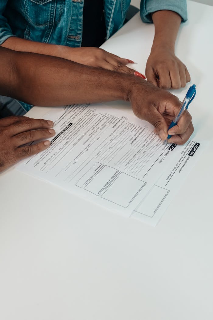 gallery-01 A couple signing adoption forms together at a desk in a professional setting.